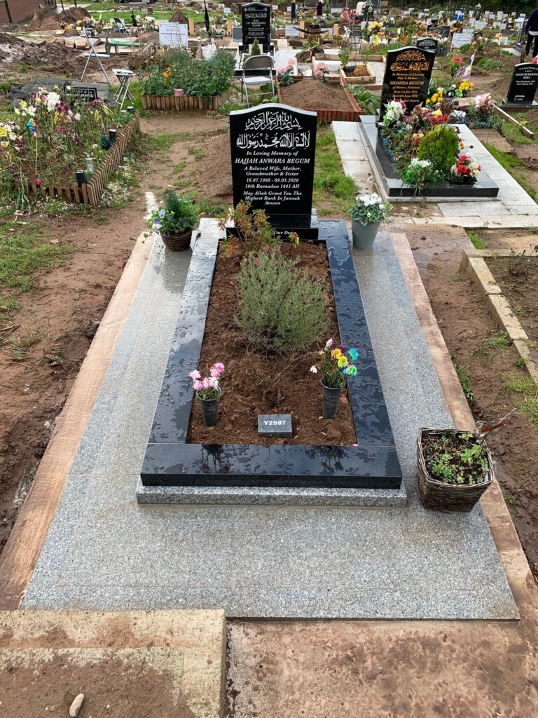 Black Standard Headstone With Kerbs and A Speckled Grey Granite Frame Landing. With Concrete And Tiling